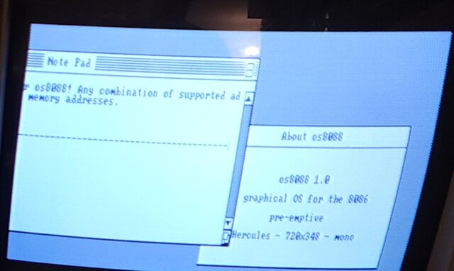 Close-up of the colour monitor: the rest of the same Note Pad window, its text continuing mid-word, with an About box open in front of it.