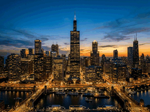 The Chicago skyline at dusk as PiXEL draws it on a 65,536-colour screen: a smooth blue sky shading to orange at the horizon, lit towers and reflections on the river.